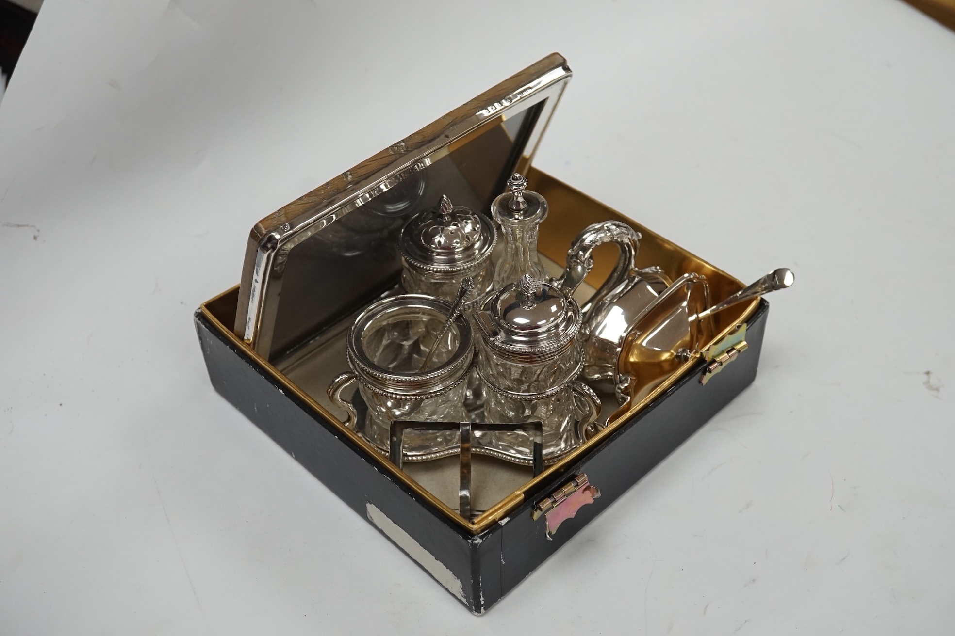 A late Victorian silver cruet stand, Jane Brownett, London, 1879, with four silver mounted bottles, different maker, Birmingham, 1879, height 67mm, together with a later silver mustard pot, a George V silver mounted phot